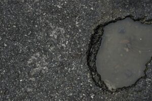 An asphalt parking lot with a pothole that has filled with water.