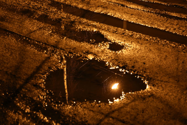 Puddles that have formed on an asphalt surface.