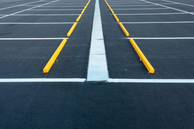 A parking lot with crisp white parking spot lines and parking blocks.
