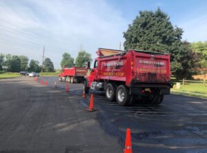 Stanley Paving dump trucks lined up on a newly milled roadway with traffic cones in place for safety during a private road paving project in New Jersey.