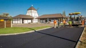 Professional driveway paving in New Jersey with a crew operating asphalt equipment to install a smooth, freshly paved surface in front of a residential property.